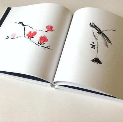 Open book with artistic illustrations of flowers and a dragonfly on a plain background